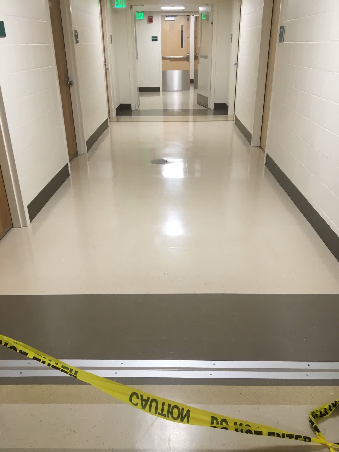 School facility refinish — LVT corridor with caution tape while coats go down