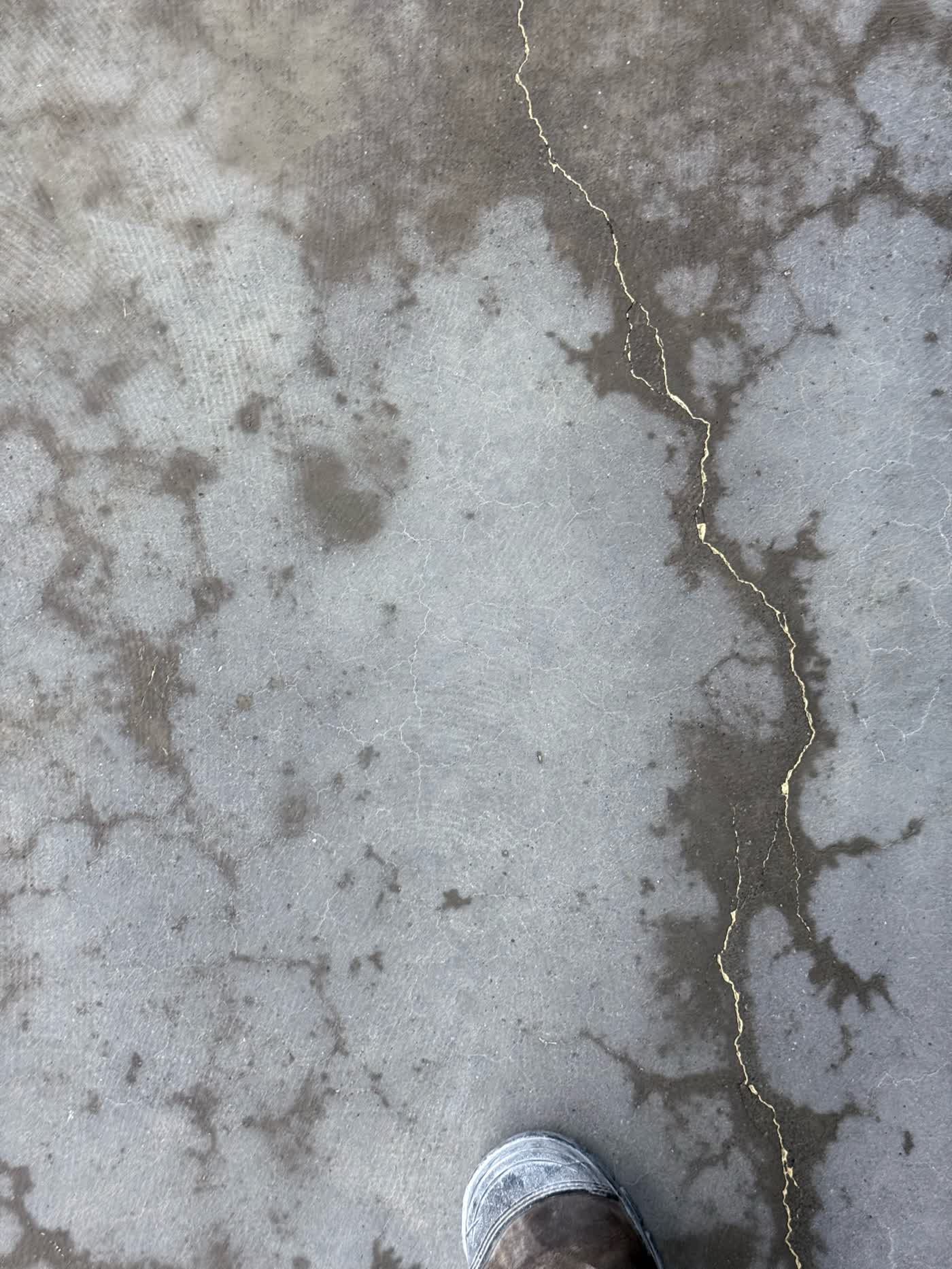Oil-contaminated slab with adhesive glue stuck in crack lines