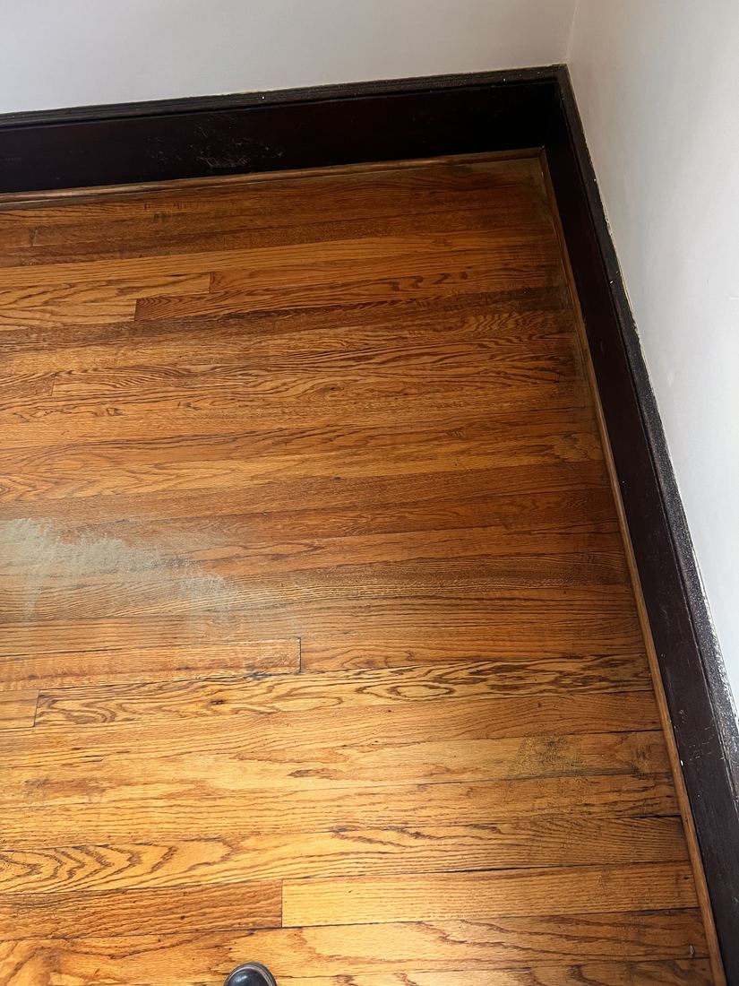 Hardwood floor with gray worn area along the baseboard