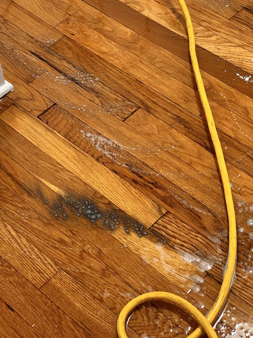 Close-up of black spray-paint overspray on hardwood boards