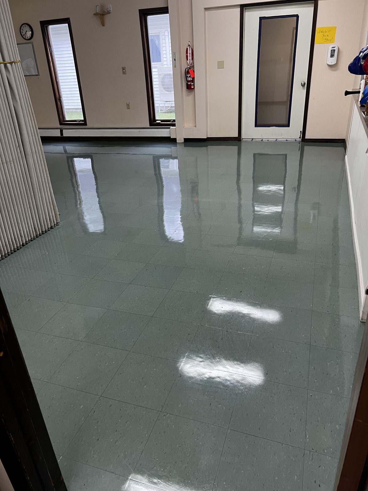Gray-green VCT room reflecting the windows and door, high-gloss finish